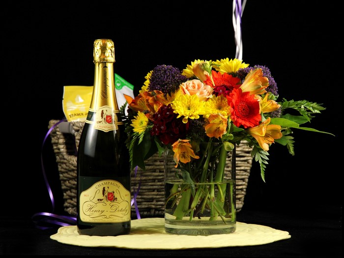 Champagne bottle and flower bouquet in a basket