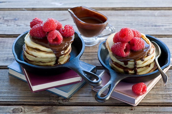 Pancakes with chocolate and raspberries in cast iron pans