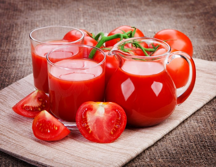 Tomato juice in glasses and jug with tomatoes