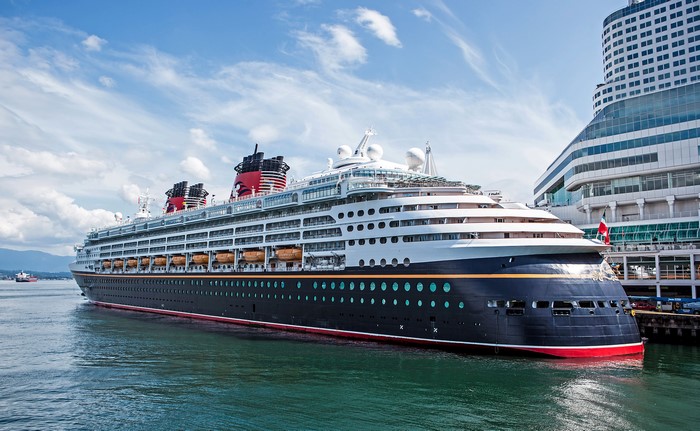 Disney Wonder cruise ship docked near a modern building