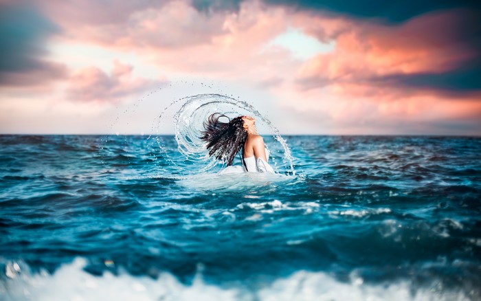 Brunette girl splashing water in the sea