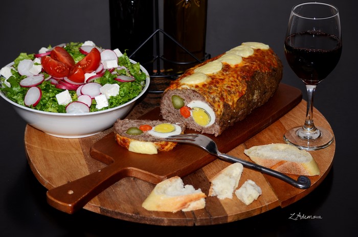 Meatloaf with eggs, salad, bread, and red wine