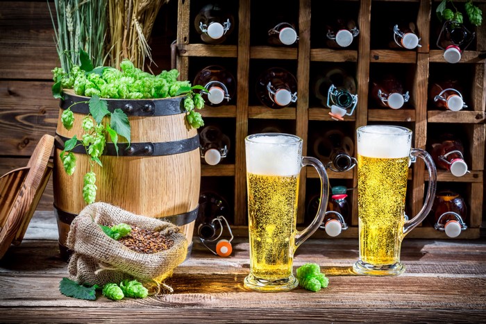 Beer barrel with hops and mugs of beer