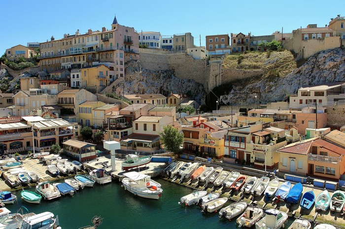 Boats docked in a harbor with houses on a hill in Marseille, France