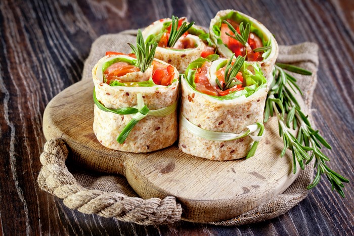 Salmon and vegetable wraps on a wooden board