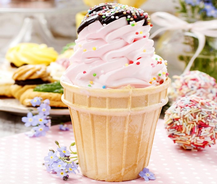 Pink ice cream in a cone with sprinkles and chocolate