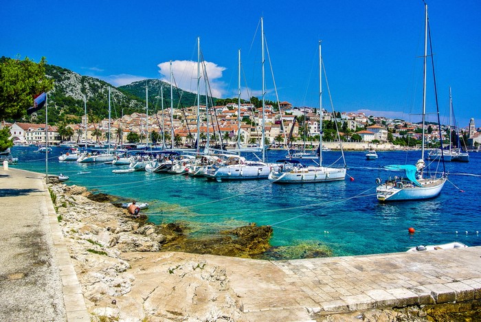 Sailboats docked in a harbor with Hvar town in the background