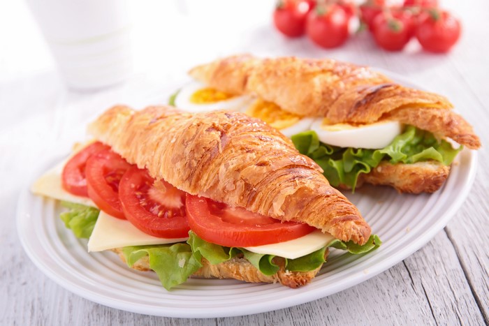 Croissant sandwiches with tomatoes, cheese, lettuce, and egg