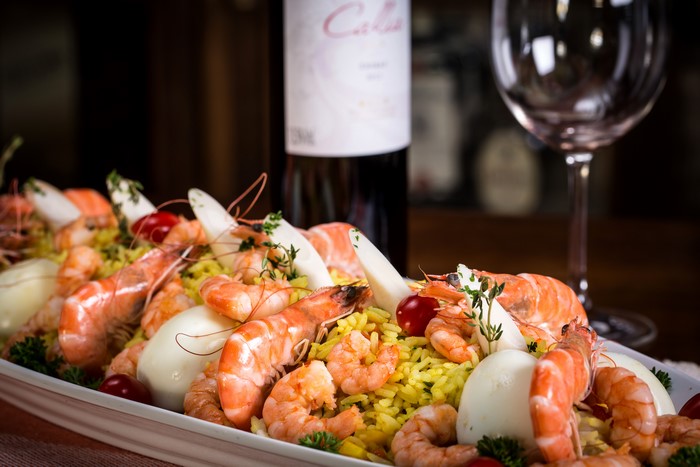 Shrimp and rice dish with wine and glass