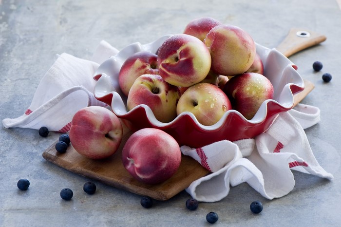 Peaches and blueberries in a red bowl