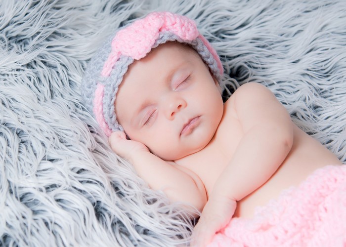 Baby sleeping on a fluffy blanket wearing a hat