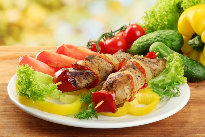 Shashlik with bell peppers, cucumbers, and tomatoes on a plate