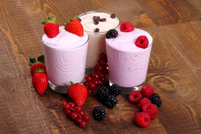 Three glasses of yogurt with berries and coffee beans