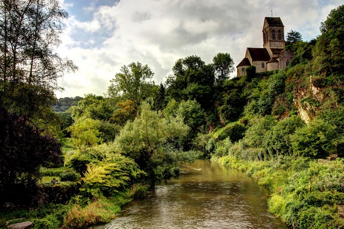 Church on a hill overlooking a river in Saint Ceneri le Gerei, France