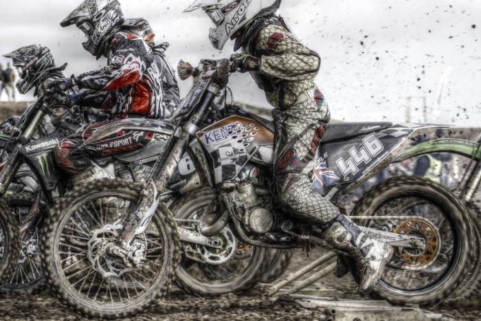 Motocross riders racing through mud