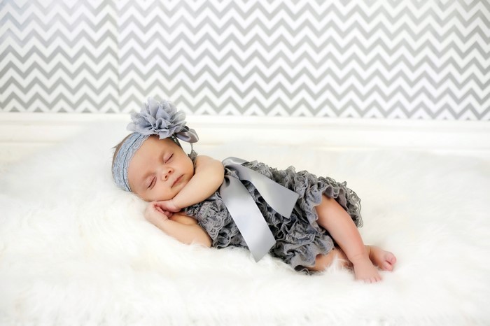 Baby girl sleeping on white fur with grey headband