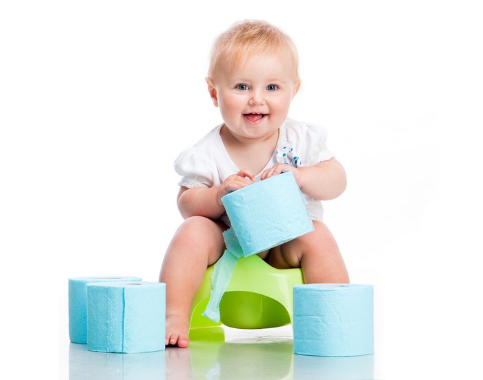 Baby sitting on a potty with toilet paper
