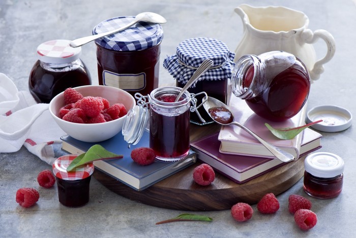 Raspberry jam in jars with fresh raspberries and books
