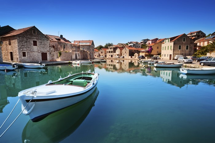 Boats docked in a Croatian harbor with stone houses