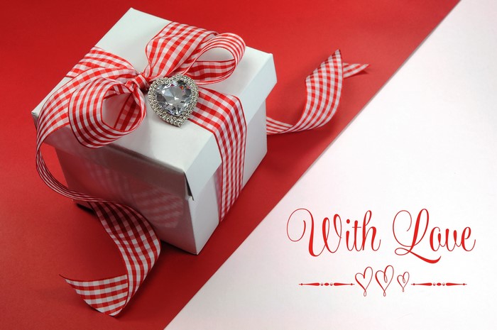 White gift box with red ribbon and heart charm