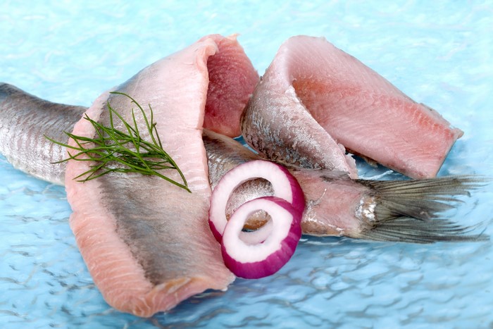 Raw fish fillets with onion rings and dill