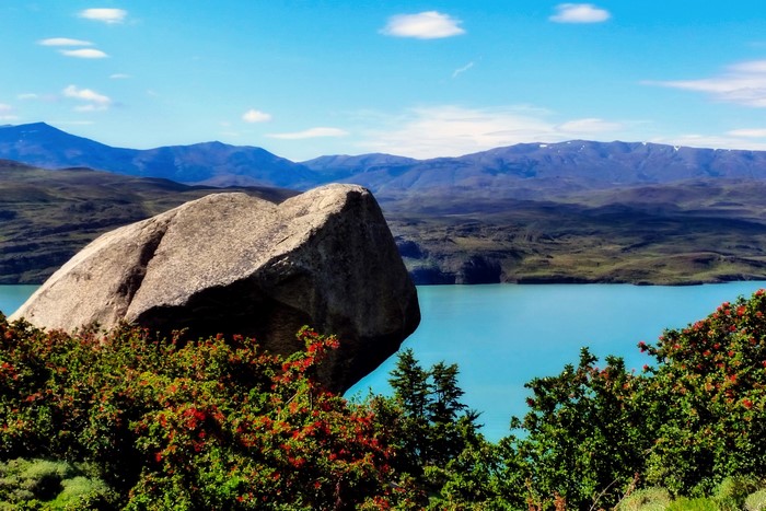 Large rock overlooking a turquoise lake and mountains in Patagonia, Argentina