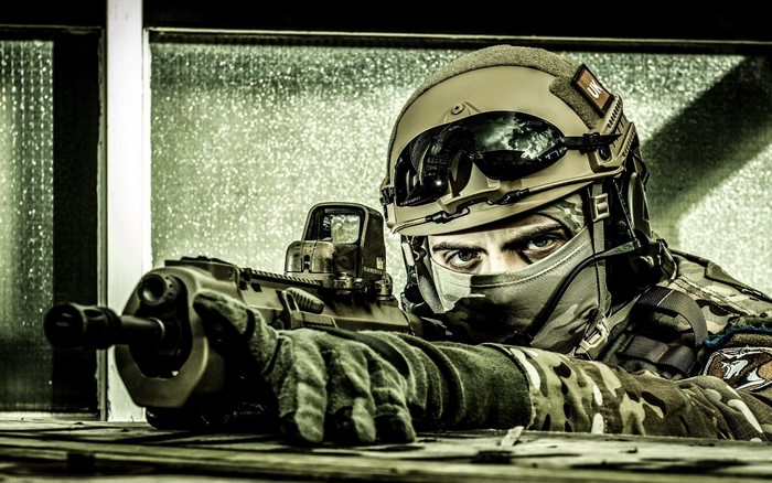 Soldier in military helmet aiming a rifle