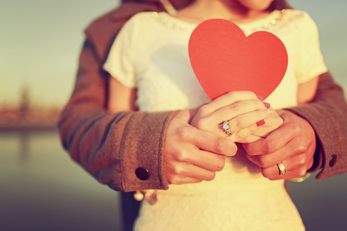 Couple holding a red heart with rings