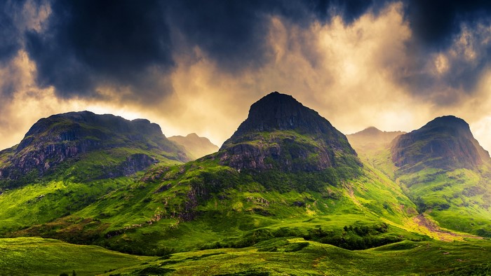 Three Sisters mountains in Glencoe, Scotland under dramatic sky