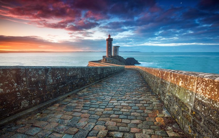 Lighthouse on a rocky island at sunset