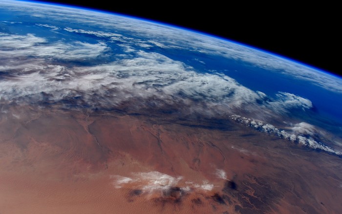 Earth's surface from space with clouds and desert
