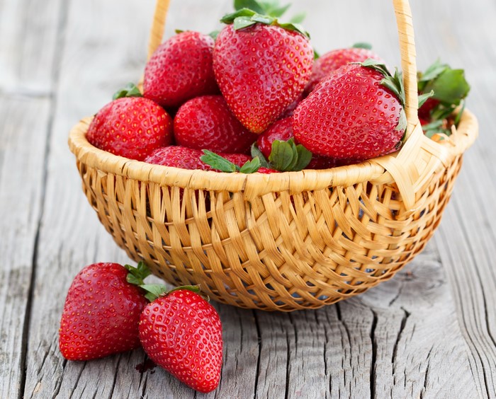 Strawberries in a wicker basket on a wooden table