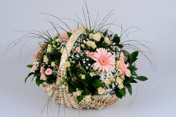 Flower arrangement in a wicker basket with roses and gerberas
