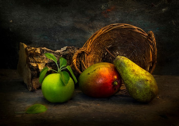 Still life with apple, mango, pear, and wicker basket