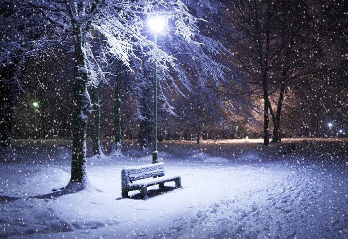 Snowy park at night with a bench and street light