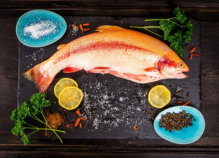 Whole Raw Fish with Spices and Lemons on Cutting Board