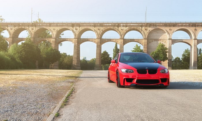 Red BMW M3 E92 parked near a stone viaduct