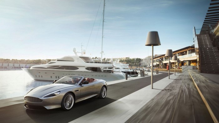 Aston Martin DB9 Cabriolet driving by yachts in a harbor
