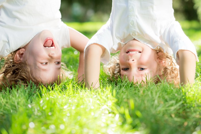 Two boys doing handstands in grass