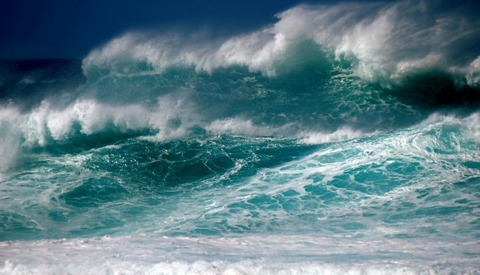 Powerful ocean waves crashing under a dark blue sky