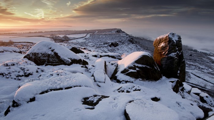 Snow-covered rocks and hills at sunrise
