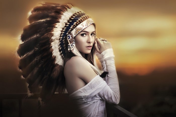 Woman wearing a Native American headdress at sunset