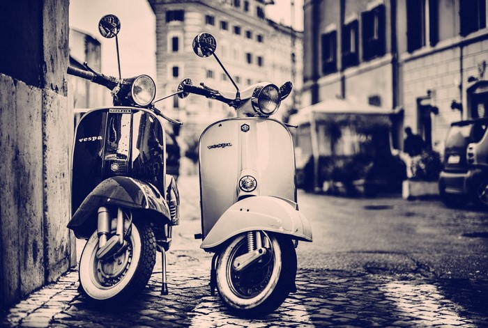 Two Vespa scooters parked on a cobblestone street