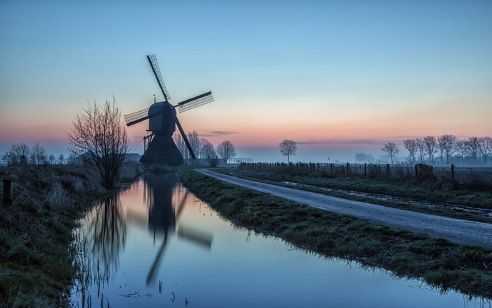 Windmill by a canal at sunrise