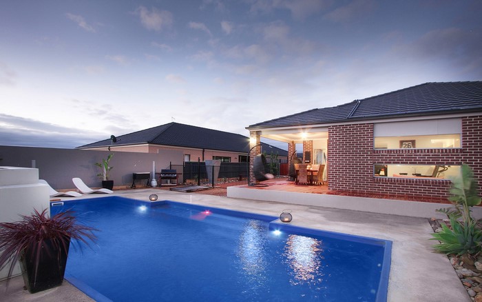 Backyard with swimming pool and patio at dusk