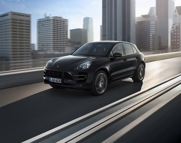 Black Porsche Macan Turbo SUV driving on a road in a city