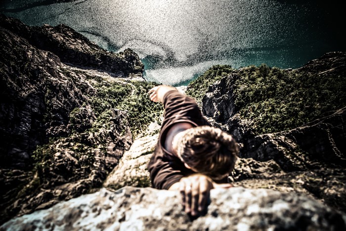 Man climbing a rocky mountain above a sea