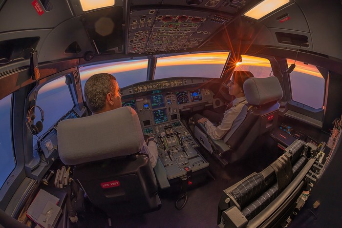 Pilots in airplane cockpit during sunset