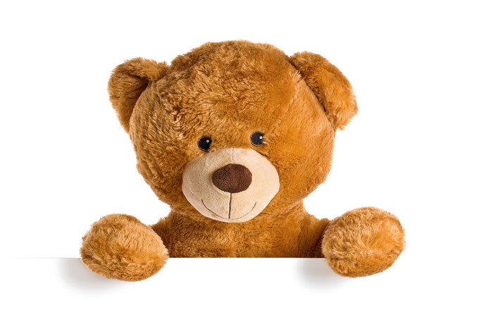 Teddy bear peeking over a white surface