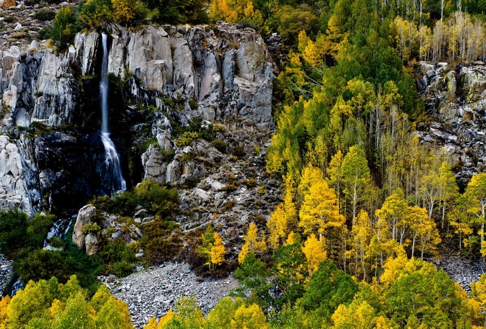 Waterfall cascading down a rocky cliff surrounded by autumn trees
